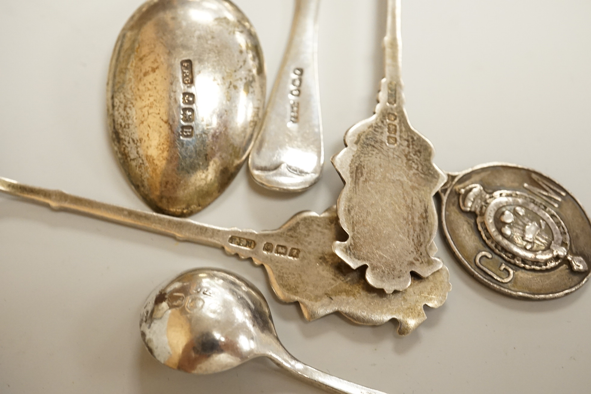 Assorted small silver including a mounted ribbed glass match strike, height 40mm, a small Scottish sterling spoon by Hamish Dawson Bowman, 76mm, a pair of George IV silver sugar tongs, commemorative spoons, an early 20th